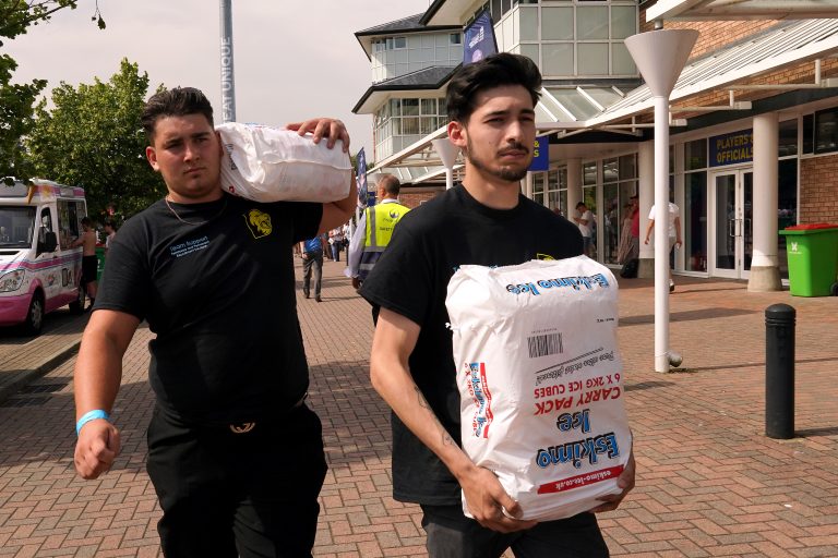 Staff carry bags of ice cubes into the ground